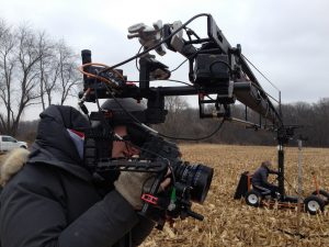 Cameraman operating a complex camera rig outdoors.